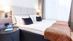 Standard dubbelrum med dubbelsäng med kuddar och täcke på Quality Hotel Winn Haninge 